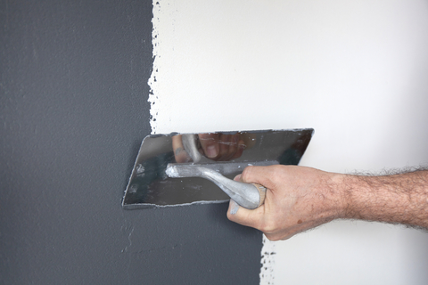 Malvern plasterers - Hand with a trowel plastering a wall with decorative plaster